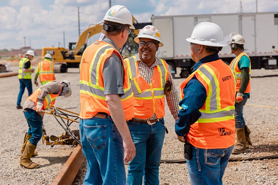 Photo of works at a construction site wearing safety vests and hard hats with Railworks logos on them